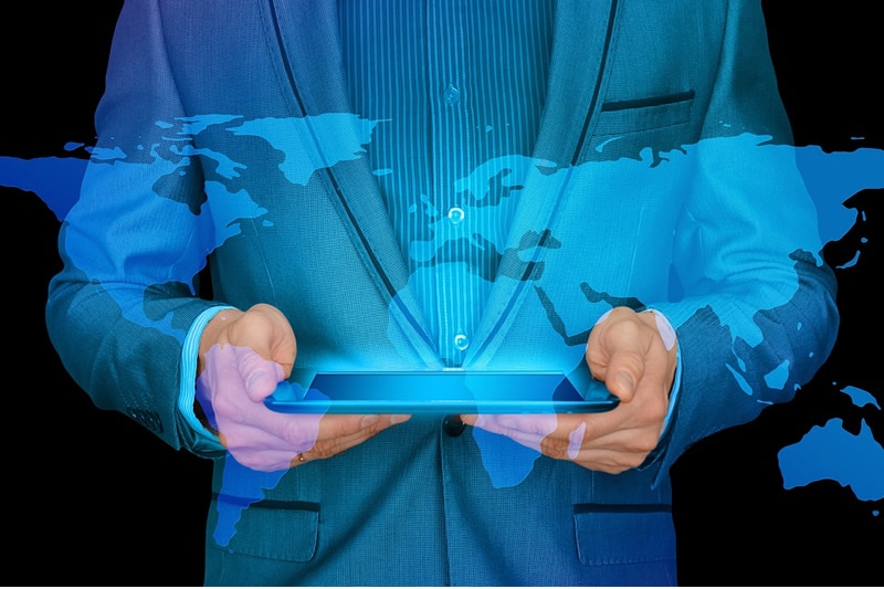 Businessman holding iPad with world map superimposed on image to illustrate our article on how to choose the right translation agency for y our e-commerce project.